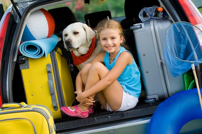 dog and girl with luggage in hatchback of car
